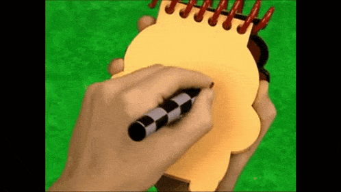 a person is writing on a yellow notebook with a pen .