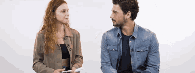 a man and a woman are sitting next to each other looking at each other