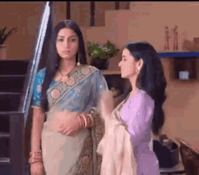 a couple of women standing next to each other in a room .