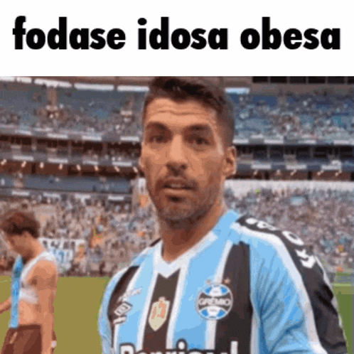 a man in a blue and black striped jersey is standing on a soccer field ..