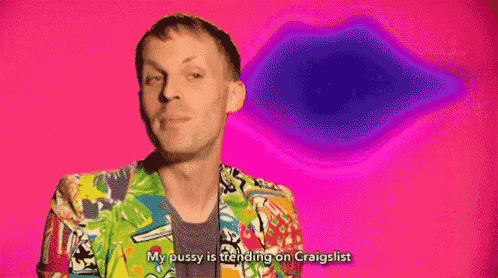 a man in a colorful jacket is standing in front of a pink background and talking .