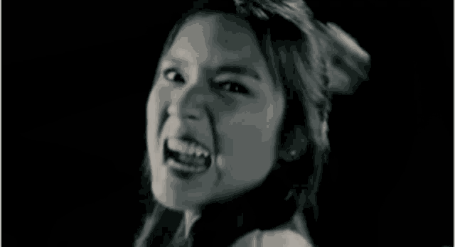 a woman is screaming in a black and white photo with her mouth open .