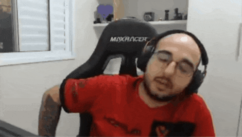 a man wearing headphones and a red shirt is sitting in a chair .
