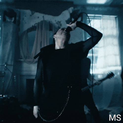 a man singing into a microphone with the letters ms behind him