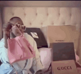 a man is holding a pink purse and talking on a cell phone .