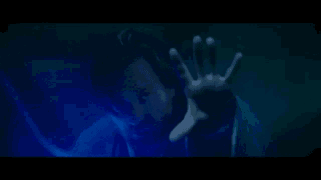 a man with a beard is reaching out his hand towards a blue light .