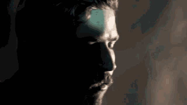 a close up of a man 's face with a beard in the dark .