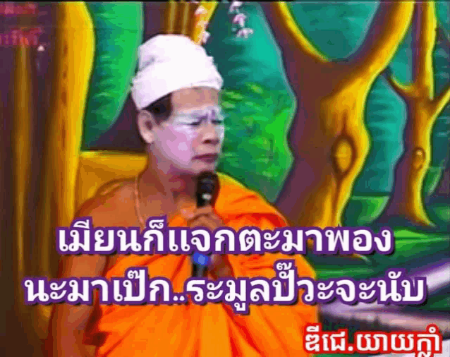 a man in an orange robe is holding a microphone in front of a painting ..