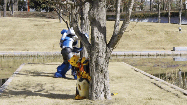 a person in a robot costume is standing next to a tree in a park