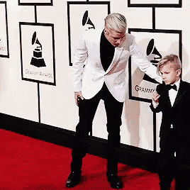 a man and a boy are standing on a red carpet at a grammy awards event .