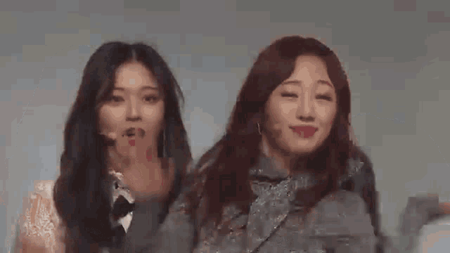 two young women are standing next to each other and waving their hands .