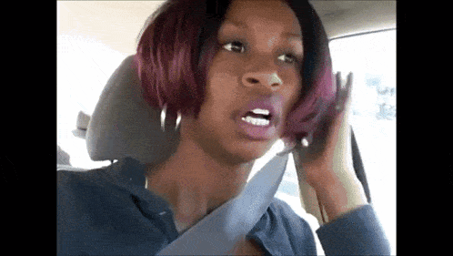 a woman with red hair is sitting in the back seat of a car talking on a cell phone