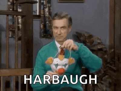 a man in a green sweater is sitting in a chair holding a toy chicken and saying harbough .