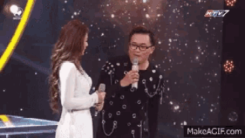 a man and a woman are standing next to each other on a stage .