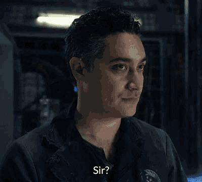 a man in a black jacket is talking to another man and the man is asking sir .