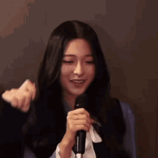 a woman is holding a microphone and smiling while a man holds her hair .