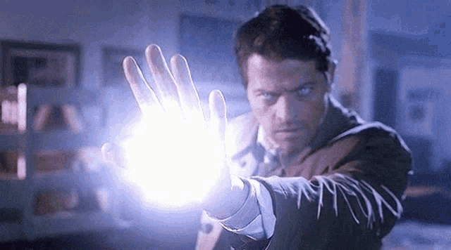 a man in a suit is holding a light coming out of his hand .