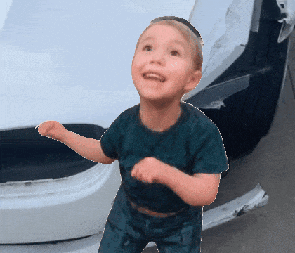 a young boy stands in front of a white car