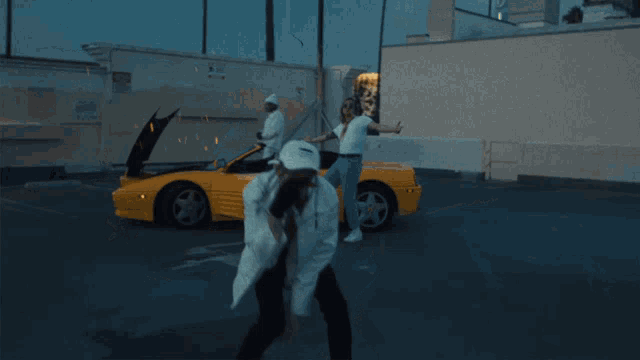 a man in a white jacket stands in front of a yellow car with the hood up
