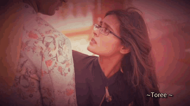 a woman wearing glasses stands next to a man in a floral shirt with the words toree below her