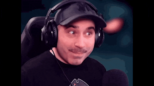 a man wearing headphones is sitting in front of a microphone and says azz
