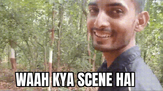 a man is smiling in front of a forest with the words waah kya scene hai