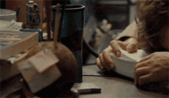 a person is laying on a desk with a stack of books and a cup of coffee .