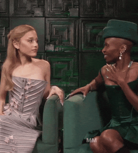 a woman in a green dress sits next to another woman