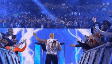 a wrestler is standing in front of a crowd with his arms outstretched