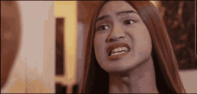 a woman with long hair is making a funny face and looking at the camera .