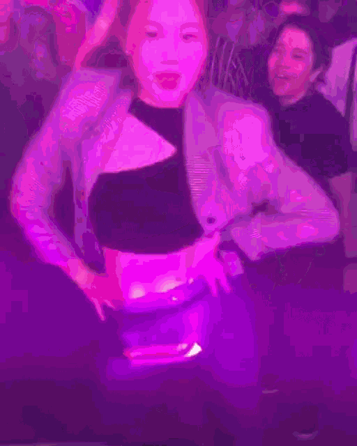 a woman in a black crop top is dancing in a crowd