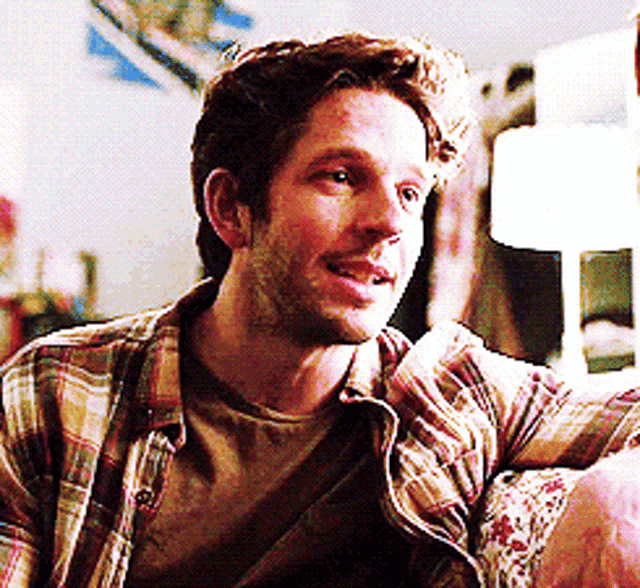 a man in a plaid shirt is sitting on a chair