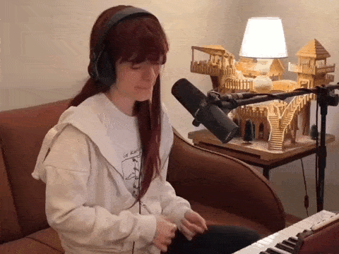 a woman wearing headphones is singing into a microphone while playing a keyboard