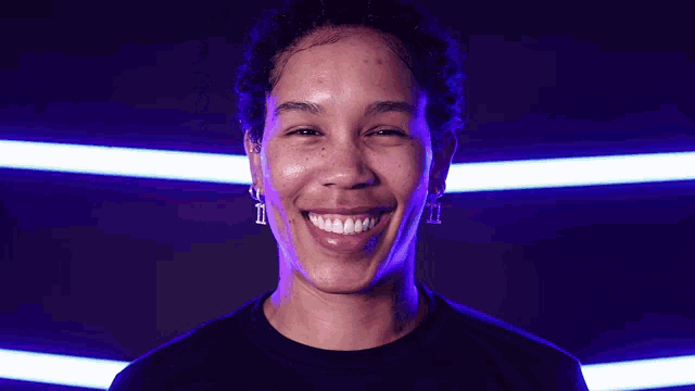 a woman in a black shirt smiles in front of a purple background