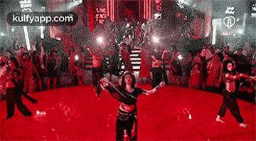 a group of people are dancing on a red carpet in front of a crowd .