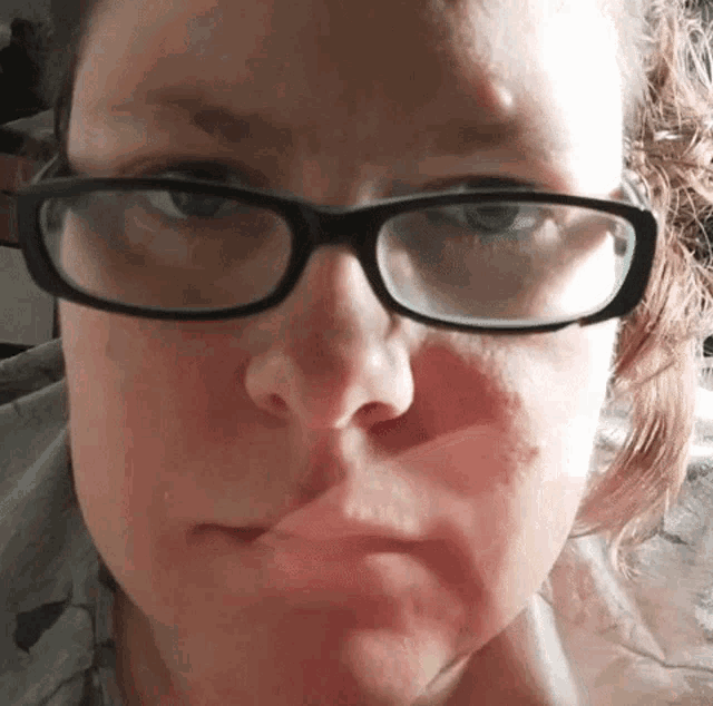 a close up of a woman 's face wearing glasses and making a funny face .