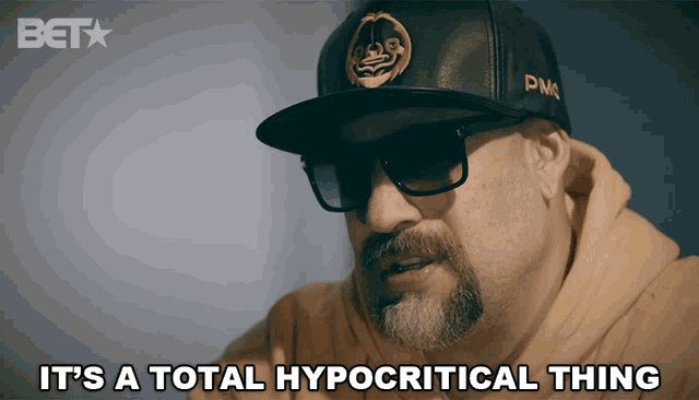 a man wearing a hat and sunglasses says " it 's a total hypocritical thing "