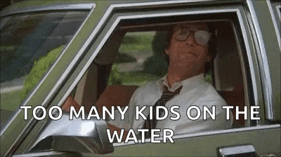 a man in a suit and tie is sitting in a car with a lot of kids on the water .