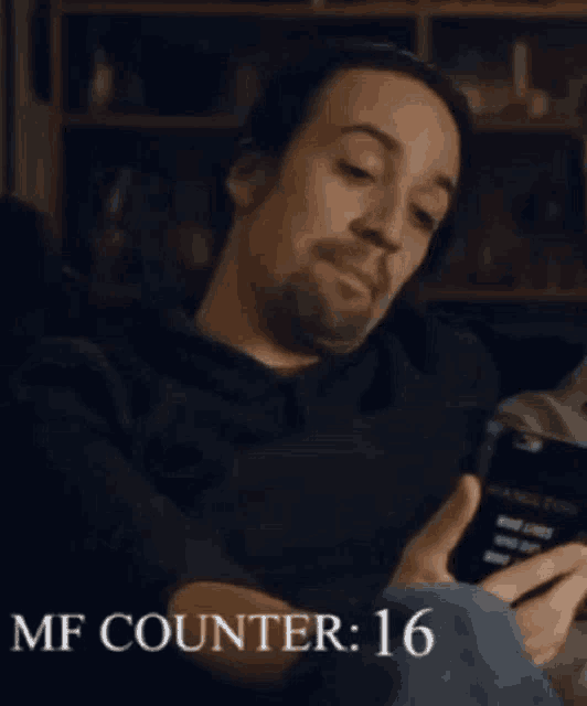 a man sitting on a couch looking at a cell phone with the words mf counter 17 written below him