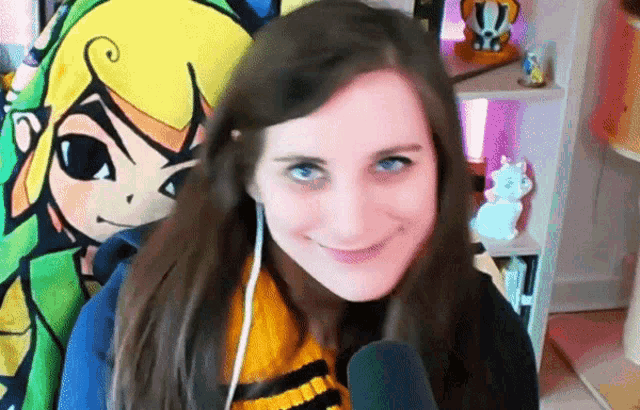a woman wearing a yellow and black scarf is smiling in front of a cartoon character