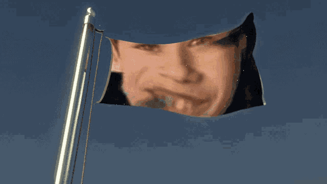 a flag with a man 's face on it is flying in the wind