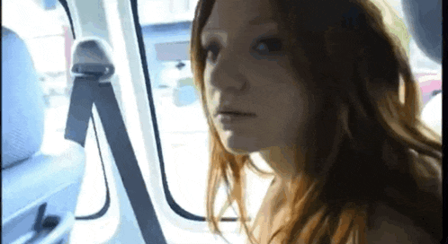 a woman with red hair is sitting in a car