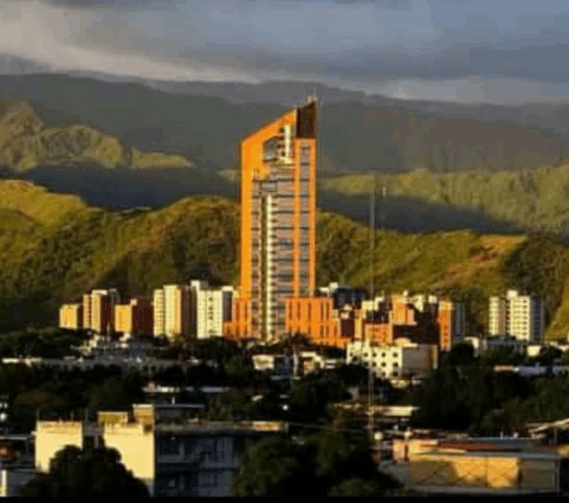 a city with mountains in the background and a very tall building in the foreground .