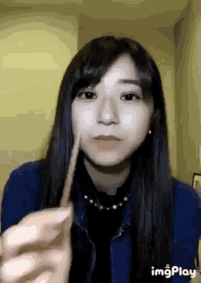 a woman with long black hair is holding a stick in her mouth and making a funny face .
