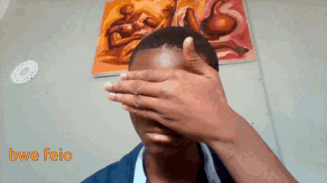 a person covering their face in front of a painting that says bwa feio on the bottom