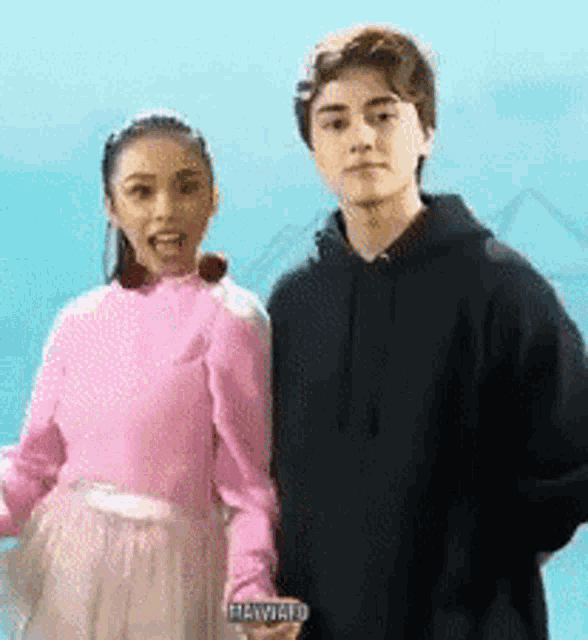 a girl in a pink sweater and a boy in a black hoodie are standing next to each other