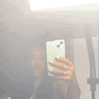 a woman is taking a selfie in front of a mirror .