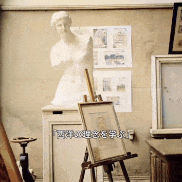 a statue of a woman sits on top of an easel in front of a wall with chinese writing on it
