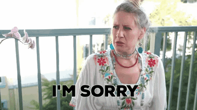 a woman is sitting on a balcony making a face and saying i 'm sorry .
