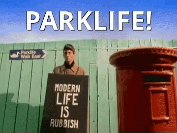 a man holding a sign that says parklife